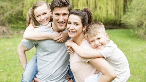 Familie mit Kindern im Huckepack Mutter und Vater tragen Sohn und Tochter im Huckepack